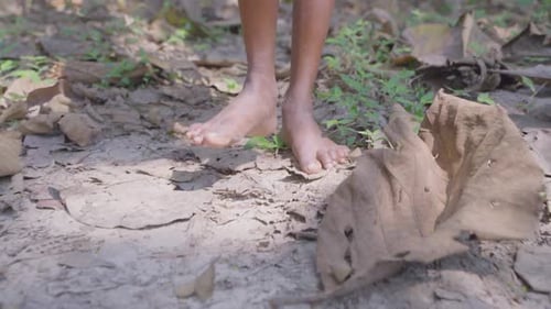 Ein Junge läuft halbnackt durch den Wald und schaut sich um.