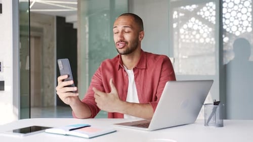 Man Speaking on Phone at Desk in Office