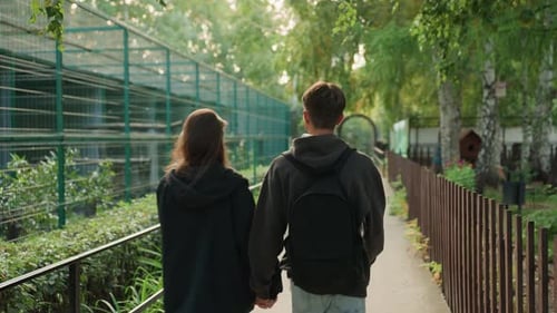 Couple Holding Hands Walking Through Park Together