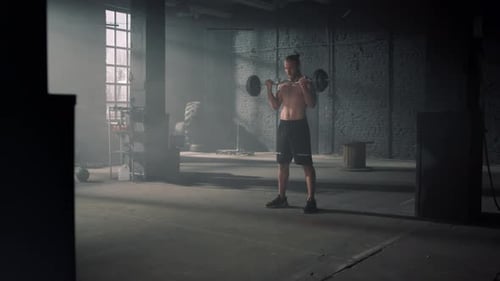 Athletic Man Lifting Weights In Dark Gym. Naked Torso Male Bodybuilder Training Biceps. Shirtless...