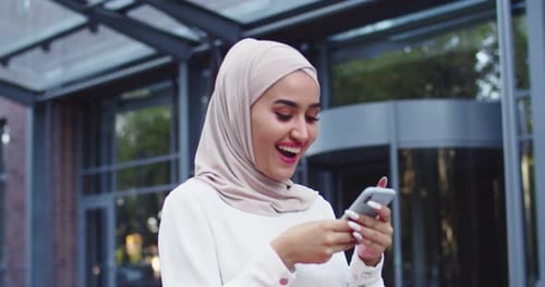 Woman in Headscarf Using Smartphone in City
