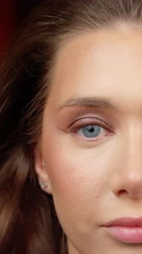 Visagist trägt Lidschatten auf das Augenlid des Models auf und verblendet dabei mit sanften Fingerbewegungen