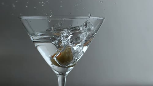 Olive Plunges into Clear Liquid Cocktail Glass