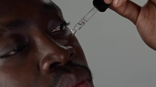 Close Up of Black Man Applying Moisturizing Serum to His Face