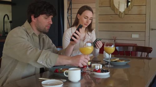 Junge Familie trinkt Kaffee und schaut sich Smartphones an Ein junges Paar, das Smartphones benutzt, ignoriert jedes