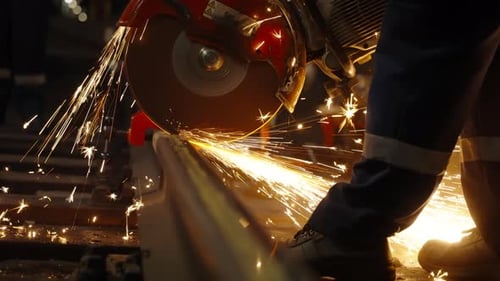 Closeup View of a Worker Using a Highspeed Grinder to Cut a Steel Rail Sending a Shower of Bright