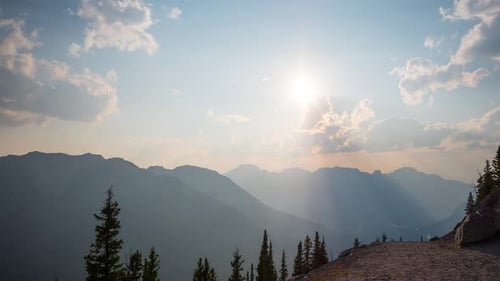 Radiant Sunlight Breaking Through Clouds Over a Majestic Mountain Range