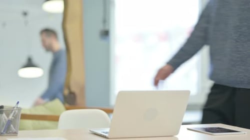 Hombre de mediana edad que regresa a la oficina y abre la computadora portátil