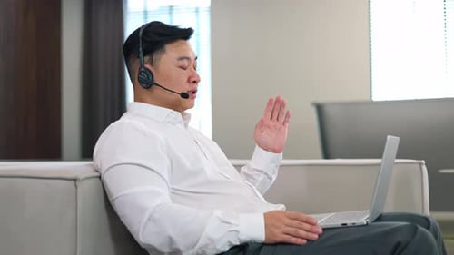 Side View of Man in Headset Having Video Chat on Laptop at Coworking Space