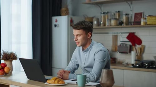 Young Adult Man Video Conferencing in Kitchen