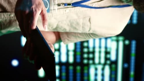 Person Holds Tablet in Front of Data Screen