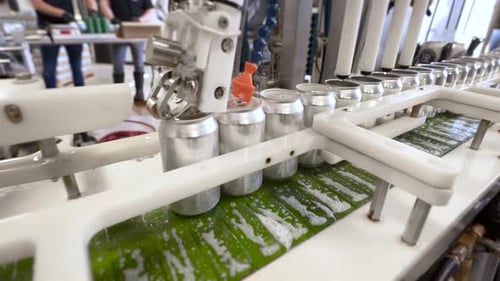 Industrial canning machine tops and seals cans, four aluminum beverage cans move down production lin
