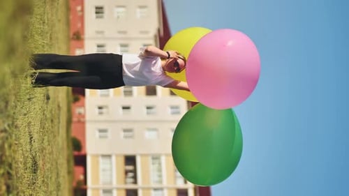 A Girl Happily Poses with Large with Colorful Balloons in the City