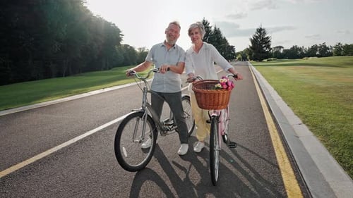 Smiling Couple Standing With Bicycles on Park Road
