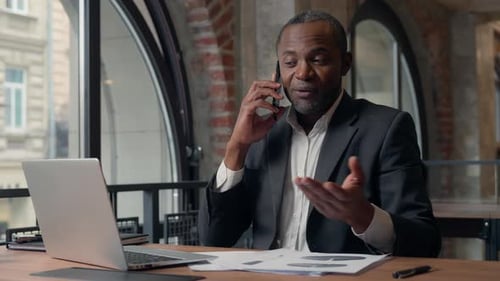 Professional man on phone at desk with laptop