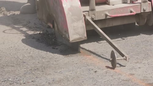 A close-up shot of an asphalt cutter at work, saw blade creating dust and sparks