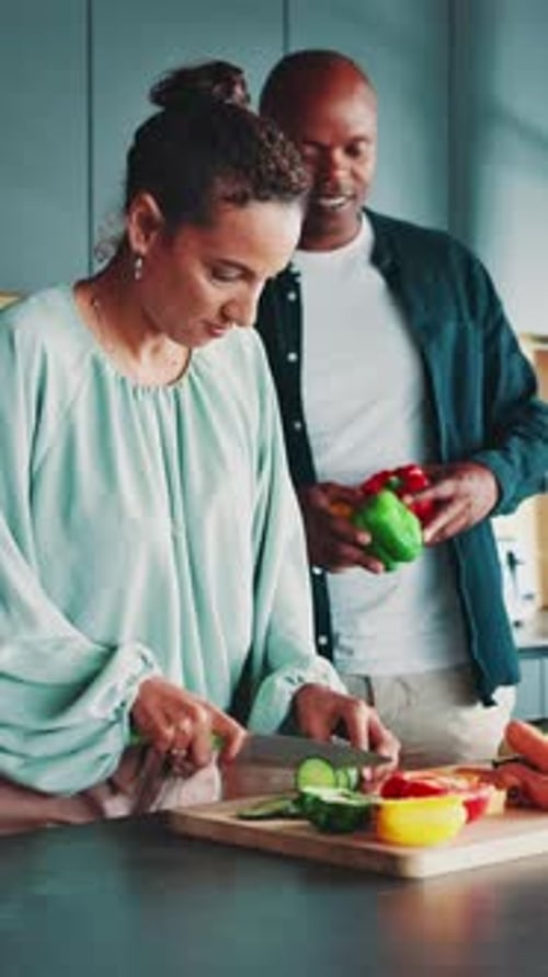 Woman Cuts Vegetables as Man Assists in Kitchen