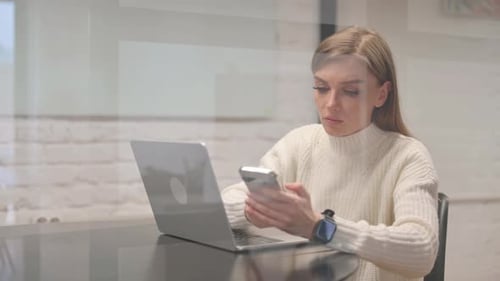 Woman Uses Laptop and Phone at Workplace