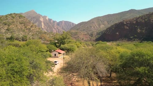 Aerial view drone flying over little village with mountains landscape and clear blue sky.