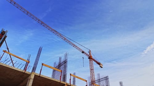 Sitio de construcción con grúa y barras de refuerzo contra el cielo azul