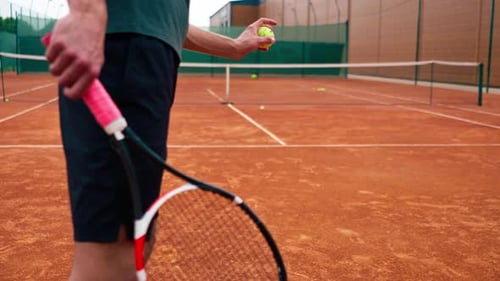 close-up professional player coach on outdoor tennis court practices strokes with racket and ball