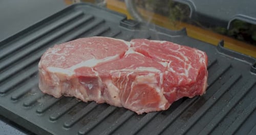 Juicy Beef Steak with Rosemary is Cooked on an Electric Grill
