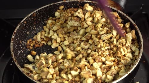 A silicone spatula stirs the chopped walnuts into the pan. Making dessert at home
