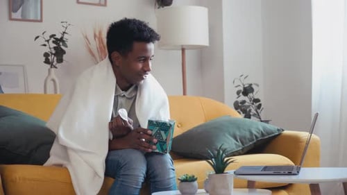 Young Adult with Curly Hair and Tissues on Couch