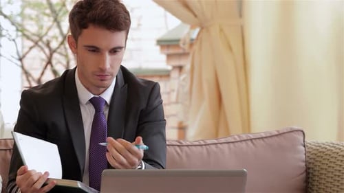 Focused Businessman Reviewing His Day Planner During a Coffee Break