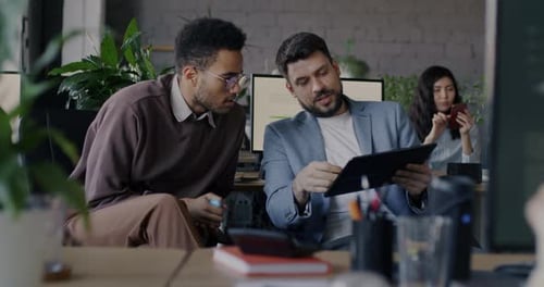 Businessmen Talking Looking at Tablet Screen Discussing Work in Modern Office