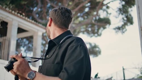 Bearded Man Takes Photos with Camera Outdoors