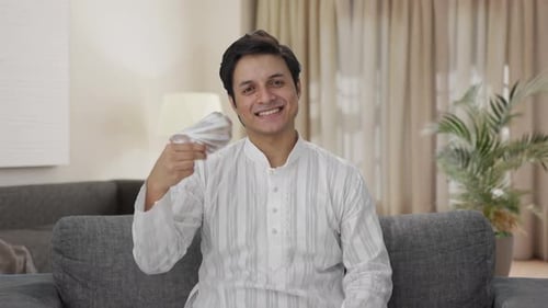 Young Adult Smiling with Banknotes on Sofa