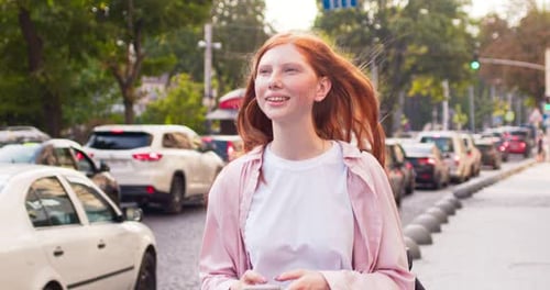 Charming Young Woman Walking Along Road and Using Smartphone Redheaded Female Lady Going Home