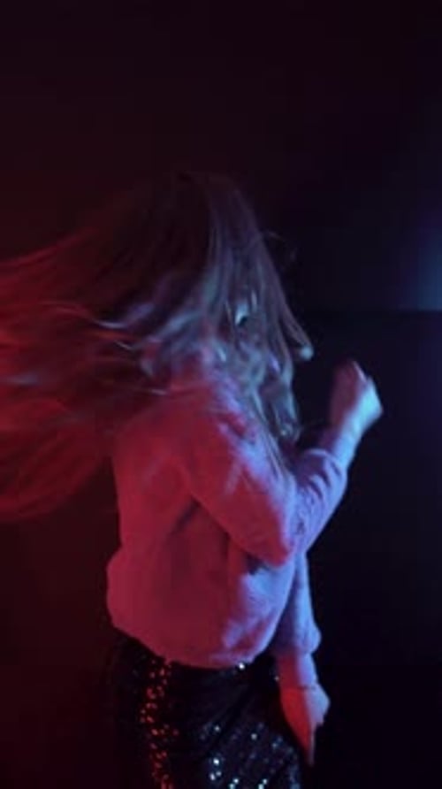 Blonde Young Girl Dancing in a Dark Blue and Red Background with Vibrant Light Effects