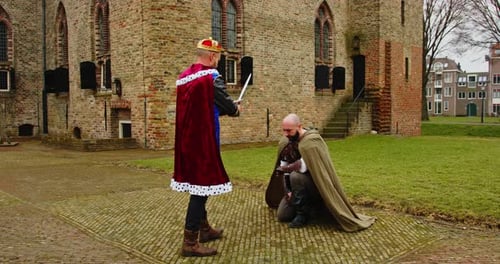 Fantasy scene: Knight kneeling down in front of king and being knighted in front of castle