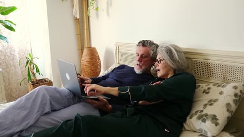 Senior Couple Relaxing in Bed with Laptop