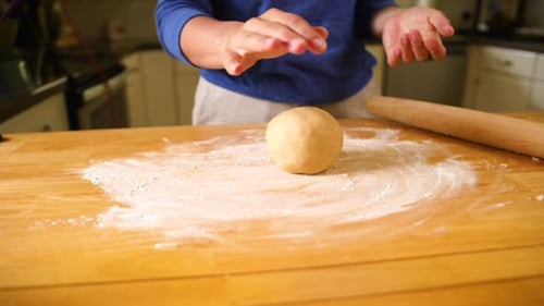 hands flattening dough ball out to bake a pie crust.