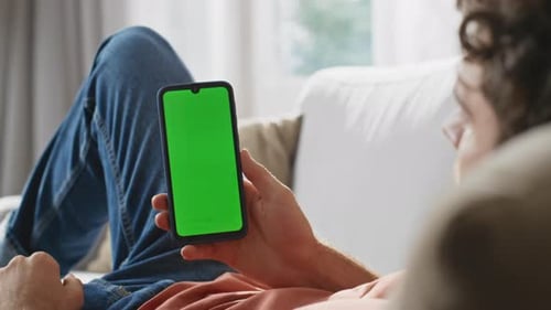Young Adult Using Smartphone with Green Screen Indoors