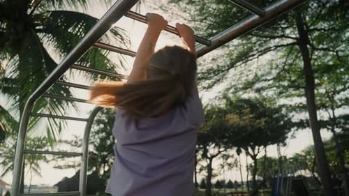 Girl Playing on Monkey Bars at Tropical Sunset