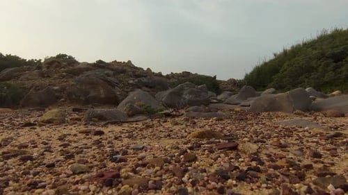 Ground view by drone in forward motion of big stones black in brown sand.