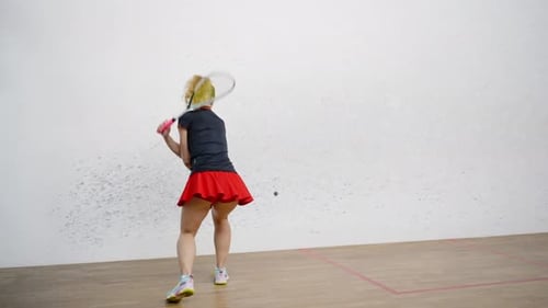 Sportive Woman in Tennis Skirt Hits Rubber Ball with Racket