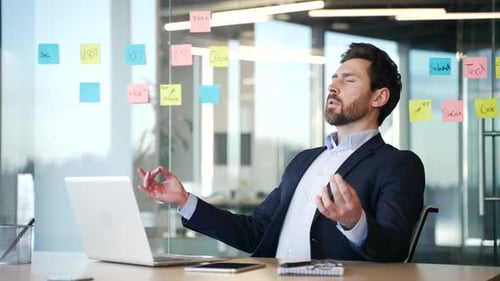 Businessman practicing mindfulness meditation at workplace. Male professional in office suit sitting