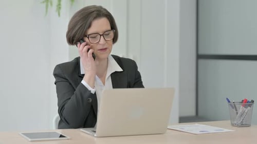 Woman Talking on Phone at Office Desk