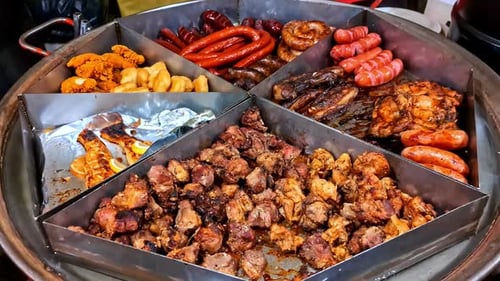 Variety of grilled meats and sausages at a street food stall at a festival.