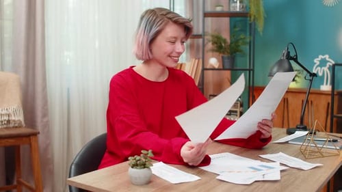 Woman Reviews Documents at Desk in Bright Room
