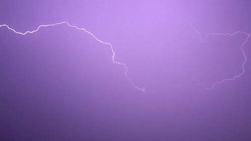 Flashes of lightning in the night sky among thunderclouds.