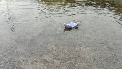 Paper Boat on Puddle During Rainstorm