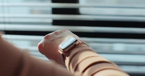 Woman Taps Gold Smart Watch By Window