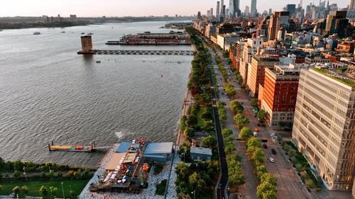 Flight above the waterfront of Hudson River. Beautiful green park and highway separating water