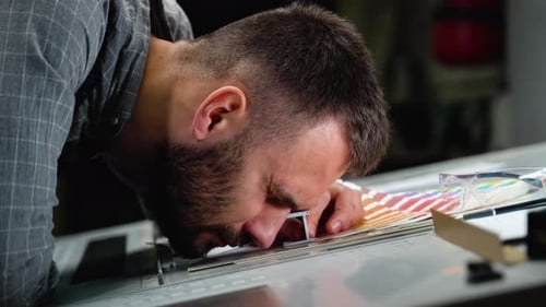 Worker in a Printing Press Factory Uses a Magnifying Glass and Check the Print Quality